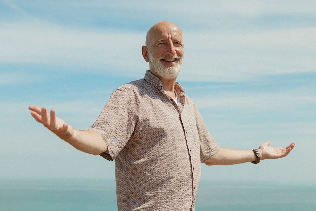 Ralf Baars mit offenen Armen unter freiem Himmel am Meer
